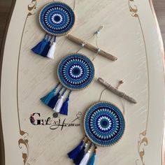 three blue and white beaded earrings with tassels hanging from them on a wall