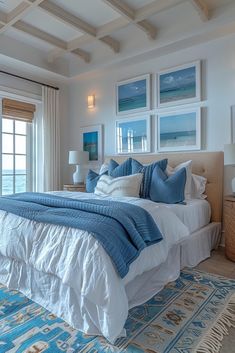 a large bed sitting in a bedroom next to a window covered in blue and white pillows