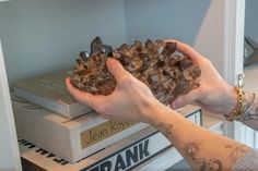 a person holding rocks in their hands on top of books