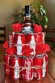 a stack of coca - cola cans with roses tied around them on a wooden table