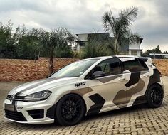 a white and black car parked in front of a brick wall