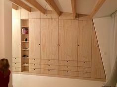 a girl is standing in the middle of a room with wooden shelves and shelving