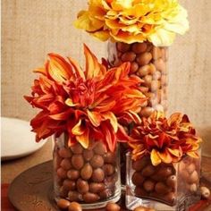 three vases filled with flowers and nuts on a table