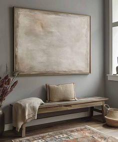 a large painting hanging on the wall next to a wooden bench in front of a window