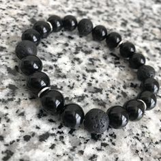 Onyx And Lava Stone 10mm Beaded Bracelet w/ Silver Accents This right here is an Embody'd Art Favorite! A great casual black beaded piece made for every occasion. The silver accents add a hint of luster and shine. And this piece will surely draw attention to you wrist! Can be stacked or worn separately or stacked with other pieces. This bracelet is crafted with quality elastic stretch cord. This bracelet is also designed to fit snug on the wrist. Laced 4 times to ensure maximum strength and hold Minimalist Onyx Beaded Bracelets With Round Beads, Minimalist Onyx Beaded Bracelet With Round Beads, Minimalist Onyx Beaded Bracelet, Black Beaded Bracelets With Spacer Beads As Gift, Adjustable Onyx Beaded Bracelet, Adjustable Round Onyx Beaded Bracelet, Black Beaded Stretch Bracelet, Gift Round Black Beaded Bracelets, Black Stretch Bracelet With Spacer Beads As Gift