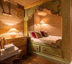 a bed in a room with wooden walls and flooring next to a table lamp