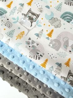 three baby blankets are stacked on top of each other, one with blue trim and the other with woodland animals