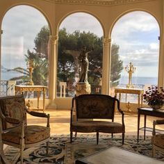 an ornate living room with large windows overlooking the ocean and statue in the middle of the room