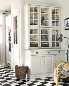 a kitchen with black and white checkered flooring, china cabinet in the corner