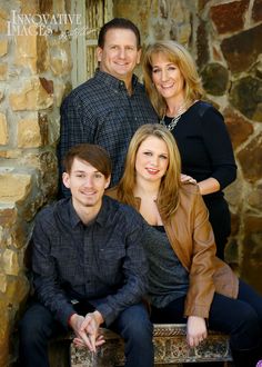 a family posing for a photo in front of a stone wall