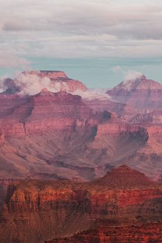 the clouds are rolling over the mountains in the desert, as seen from an overlook point