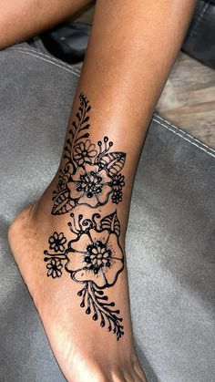 a woman's foot with black and white flowers on the bottom of her leg