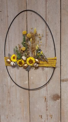 a circular metal frame with flowers and birds on it, sitting against a wooden wall