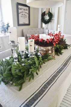 a dining room table decorated for christmas with greenery and candles