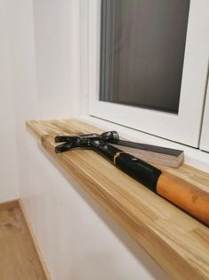 a pair of black gloves sitting on top of a wooden shelf next to a window