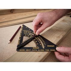 a person using a wooden ruler to measure the height of a triangle on a piece of wood