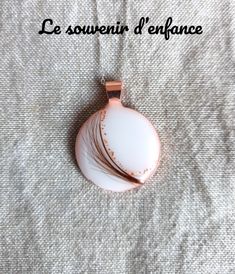 an image of a pendant with feathers on it's back side and the words les souveneinir d'enfrance written below