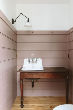 a bathroom with pink walls and wooden flooring next to a white sink on top of a table