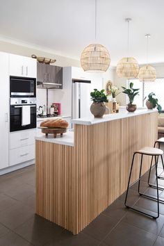 a kitchen with an island and stools in front of the counter top that has plants on it