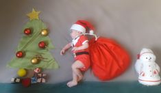 a small child wearing a santa hat and carrying a bag next to a christmas tree