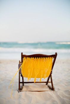 a yellow chair sitting on top of a sandy beach