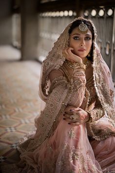 a woman in a bridal gown sitting on the floor with her hand under her chin