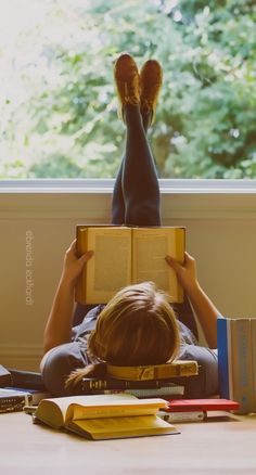 a person laying on the floor reading a book with their feet up in front of them