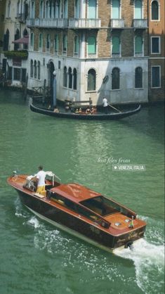 a small boat traveling down a river next to a tall building on the other side