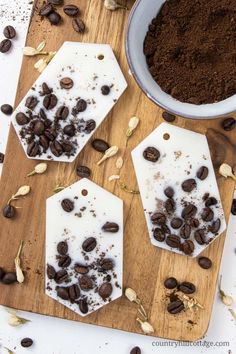 three pieces of chocolate sitting on top of a wooden cutting board next to some coffee beans