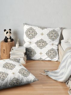 a panda bear sitting on top of a wooden floor next to pillows and other items