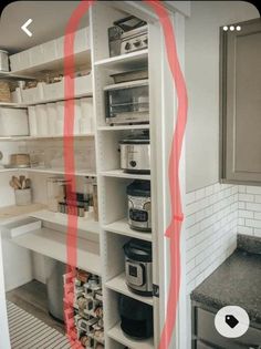 a kitchen with white cabinets and red tape on the wall next to an open pantry