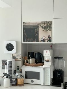 a kitchen with white cupboards and appliances on the counter top, including a microwave oven