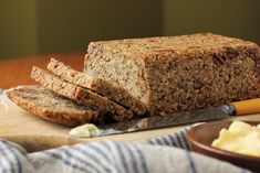 a loaf of bread sitting on top of a cutting board next to butter and a knife