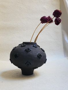 a black vase with two flowers in it