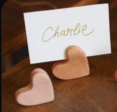 two heart shaped magnets sitting on top of a wooden table next to a card