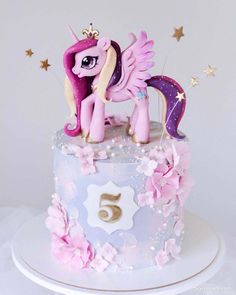 a pink and purple cake with a pony on top that has stars around the edges