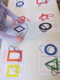 a young child is playing with scissors on the table in front of some cut out shapes