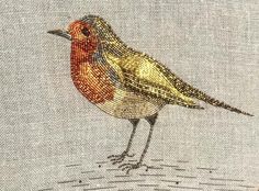 a small bird is sitting on the edge of a piece of fabric with gold and red accents