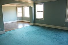 an empty room with blue carpet and two windows