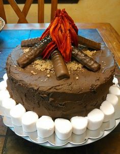 a large chocolate cake with frosting and decorations on it's top sitting on a table