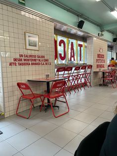 people sitting at tables in a cafeteria with signs on the wall and tiled flooring