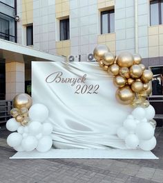 a large white and gold balloon arch in front of a building