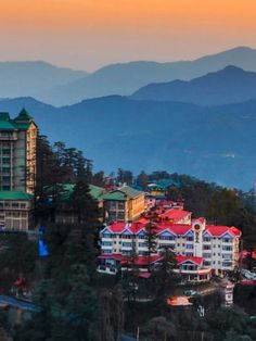 the city is surrounded by mountains in the evening light, with colorful buildings and green roof tops