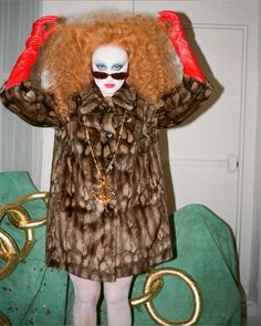 a woman with red hair and makeup wearing a fur coat