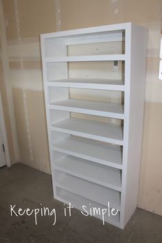 an empty white book shelf in the corner of a room