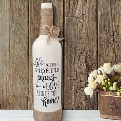 a vase with flowers next to a bottle that says life must be unexpected places love makes you home