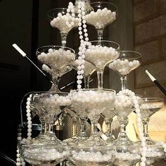 many wine glasses are stacked on top of each other with pearls and beads hanging from them