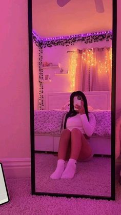 a woman taking a selfie in front of a mirror with pink lights behind her