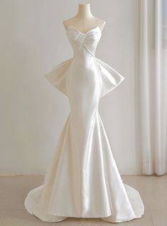 a white wedding dress on a mannequin in front of a curtained window