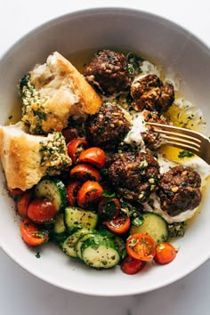 a white bowl filled with meatballs and veggies